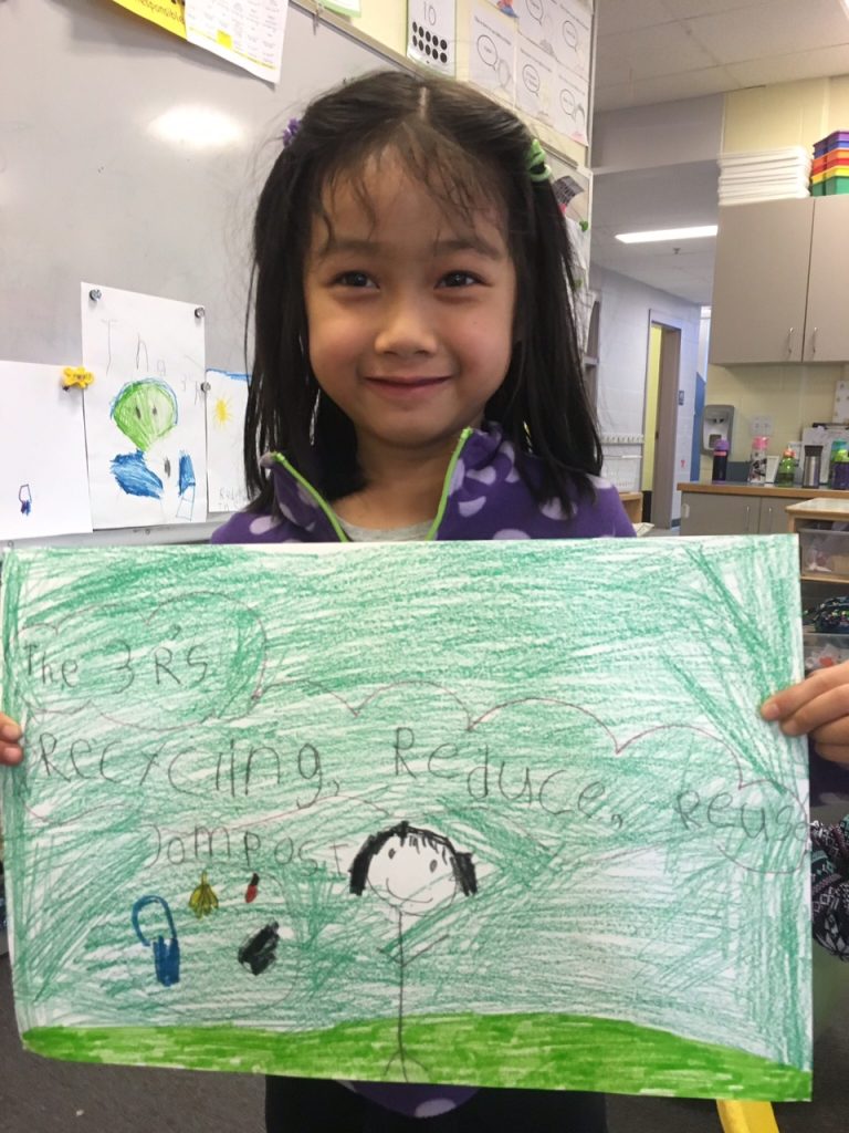 Student holding up a drawing they did about recycling.