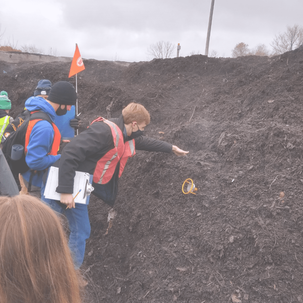 A tour goer touches the hot compost after taking a temperature with a probe.